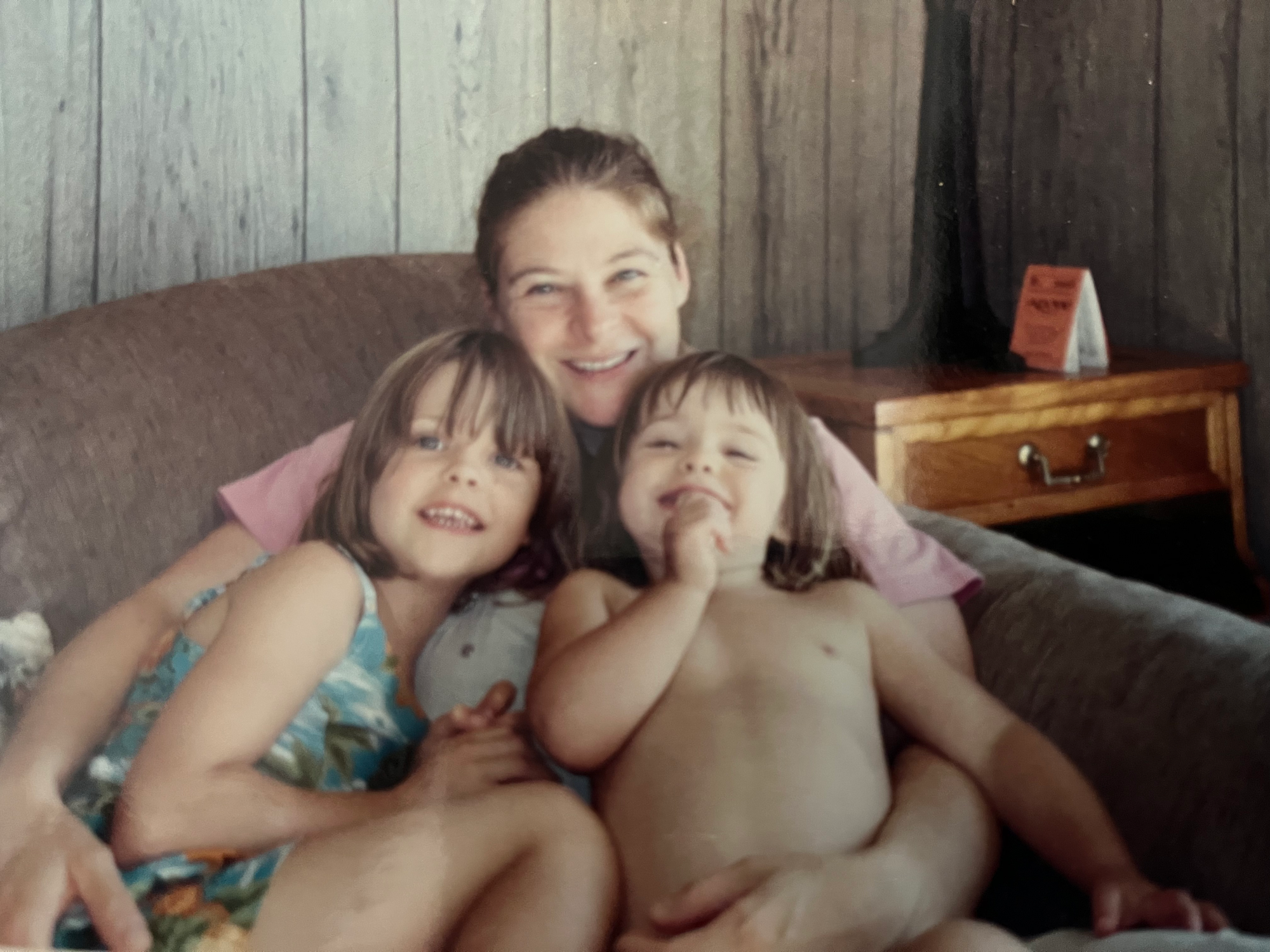 A photo of me with my kids, aged about 5 and 2. We're sitting on a couch with them crammed into my lap and we all look very happy.