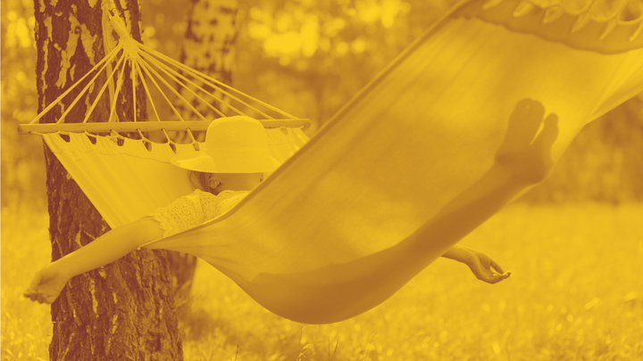 A photo of a woman lying in a hammock with her arms out and a hat over her face.