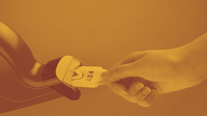 A photo of a hand pulling a piece of paper with a number on it from a machine.