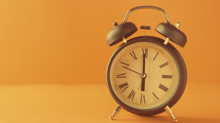 A photo of an old fashioned alarm clock with bells on the top.