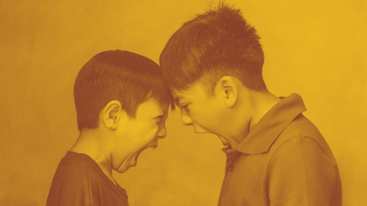 a photo of two young boys standing with their foreheads touching. they both appear to be yelling, mouths wide open.