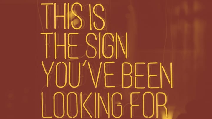 A photo of a neon sign that says, all caps, THIS IS THE SIGN YOU'VE BEEN LOOKING FOR