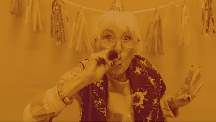 A photo of an elderly white woman with a birthday hat blowing a paper tooter.